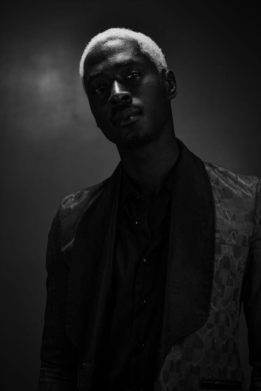 Portrait in mustard jacket against teal backdrop