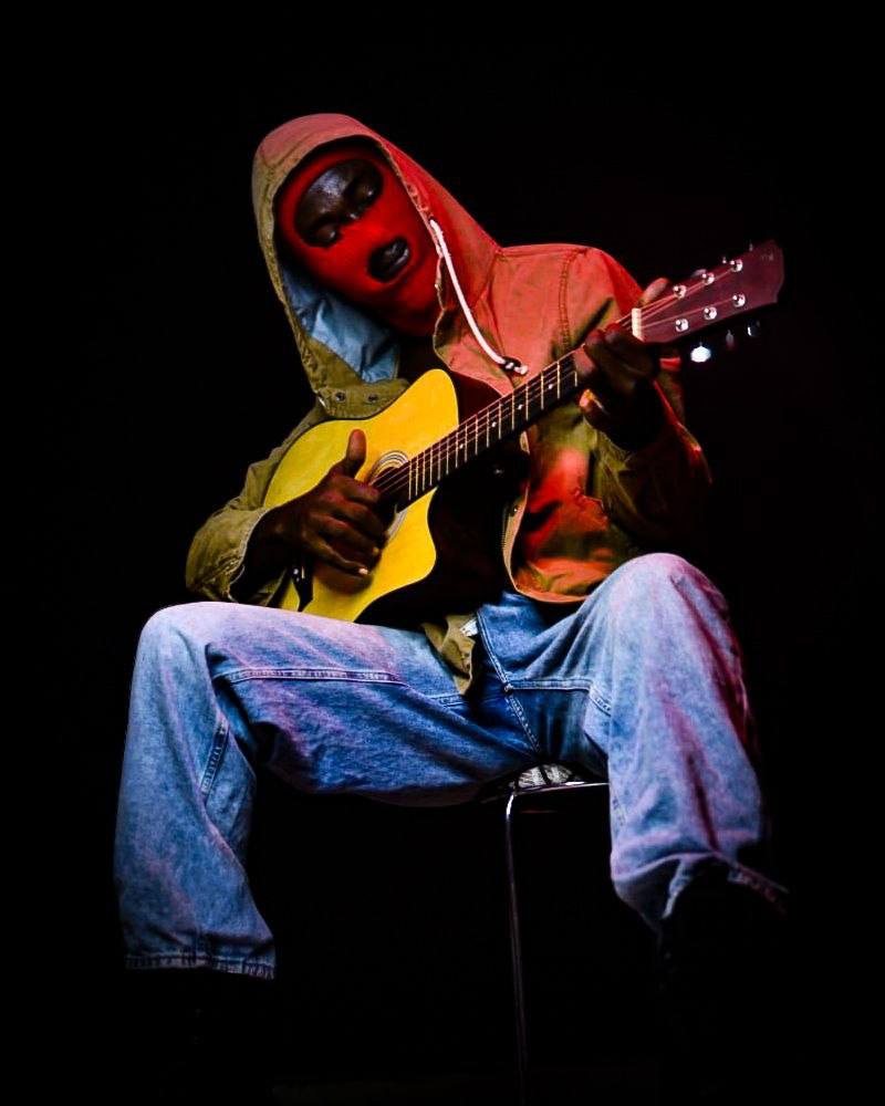 Masked guitarist performance close, red gel
